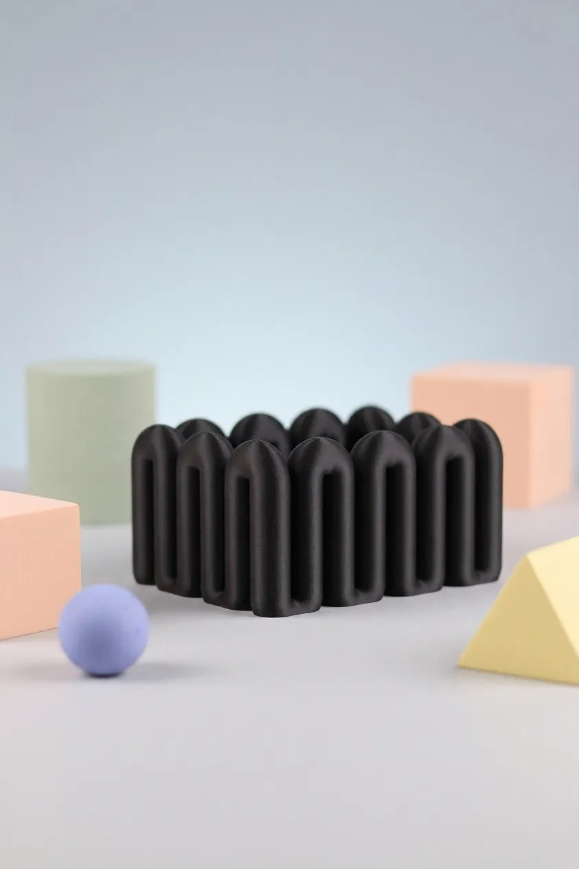 Black sculptural Wibble organiser shown with pastel geometric props