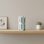Two-part Wibble vase displayed on a wooden shelf in a calm neutral interior.